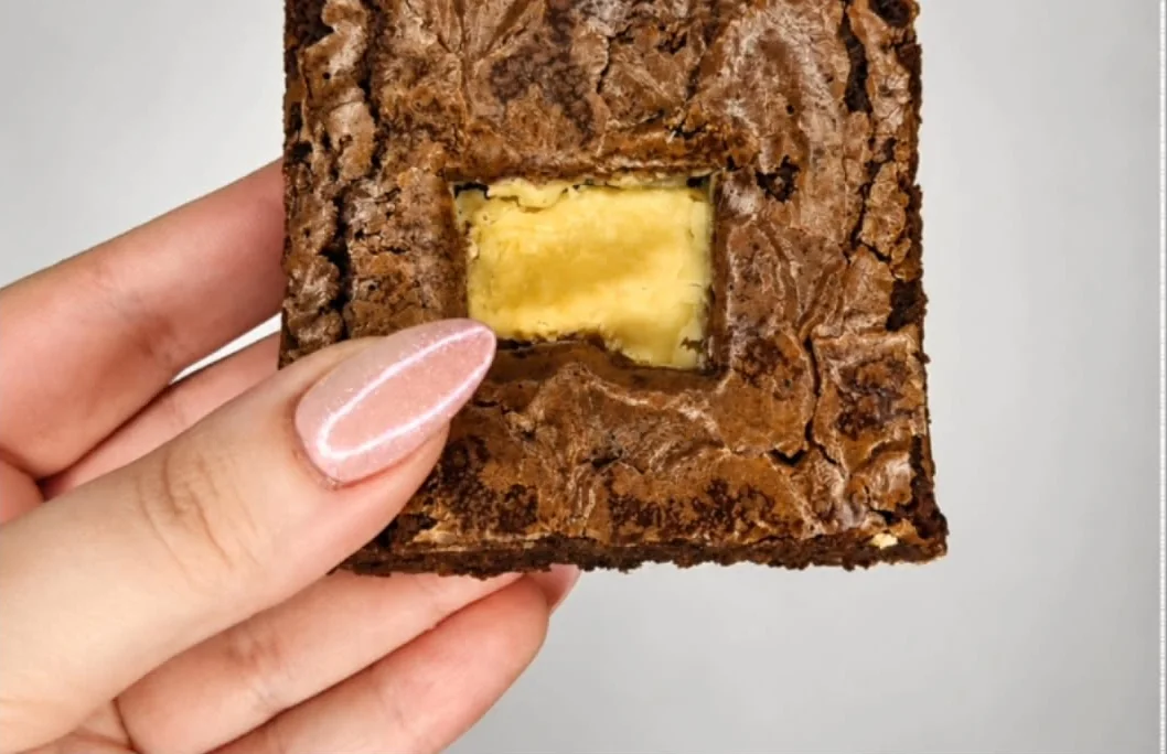 Brownie visto por cima, com a casquinha brilhante e um pedaço de chocolate branco