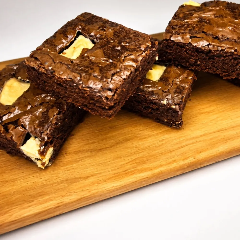 Brownies tradicionais cortados sobre uma tábua de madeira, com pedaços de chocolate branco